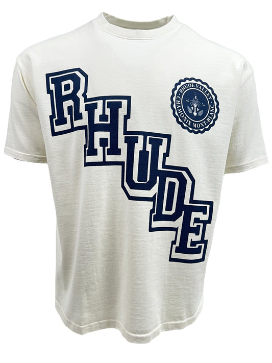 RHUDE COLLEGIATE CREST TEE VTG WHITE featuring the word "RHUDE" in large blue block letters and a blue circular emblem with the text "RHUDE VALLEY MOUNTAINEERS," crafted from 100% cotton. This RHUDE product perfectly blends classic style with a bold logo graphic design.