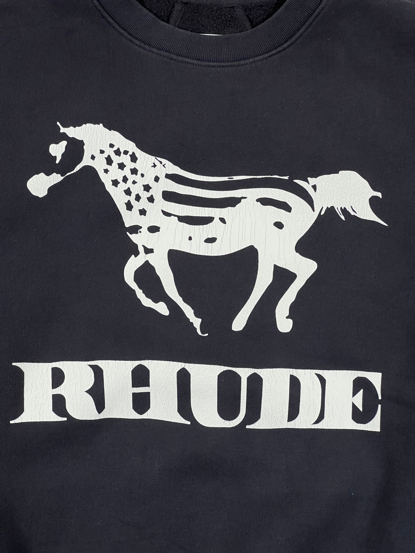 The Rhude Dinero Crewneck Vintage Black/White by RHUDE features a white horse with an American flag pattern above "RHUDE," crafted from 100% cotton for comfort and style.