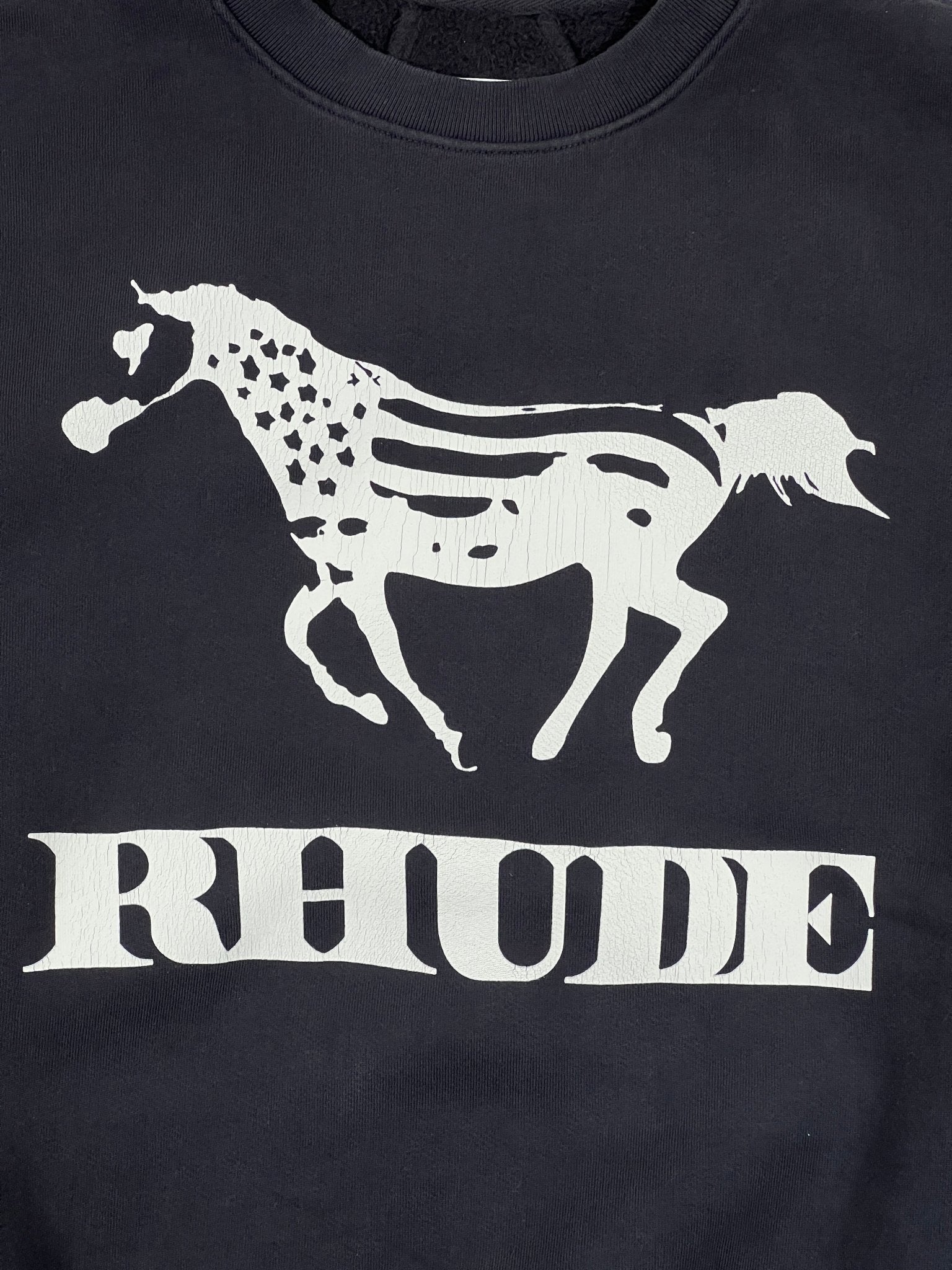 The Rhude Dinero Crewneck Vintage Black/White by RHUDE features a white horse with an American flag pattern above "RHUDE," crafted from 100% cotton for comfort and style.