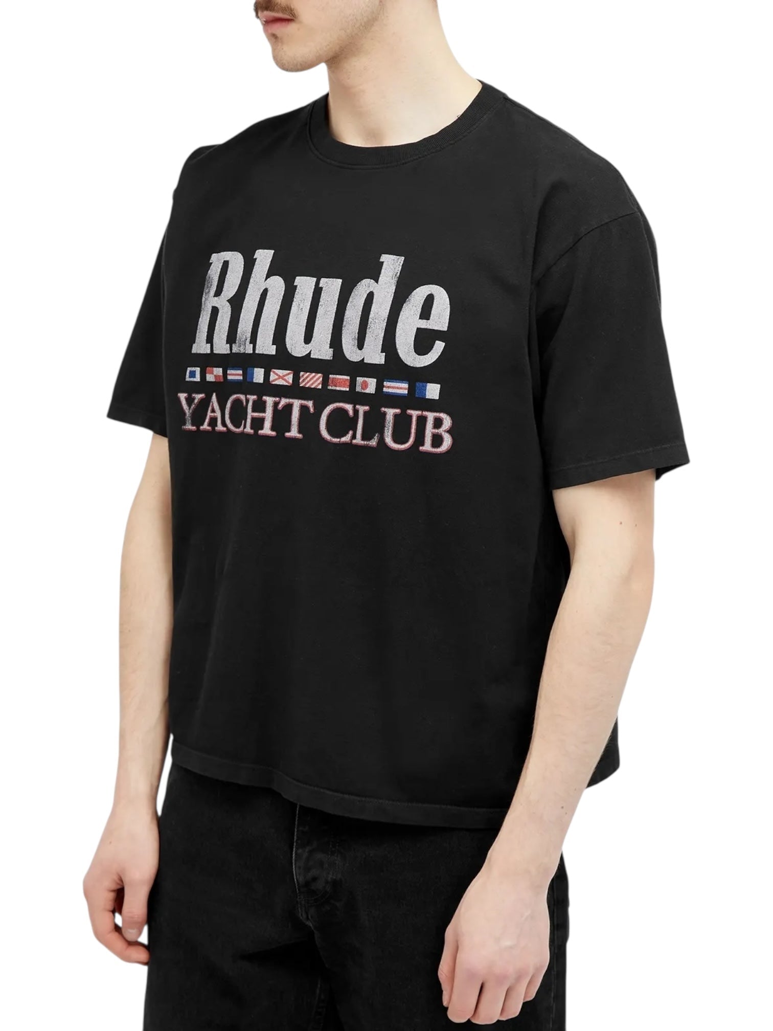 Someone in the RHUDE FLAG TEE BLK by RHUDE, featuring "Rhude" and "Yacht Club" text with a row of small flag graphics on the front, displays luxury graphic tee style with understated American-inspired design.