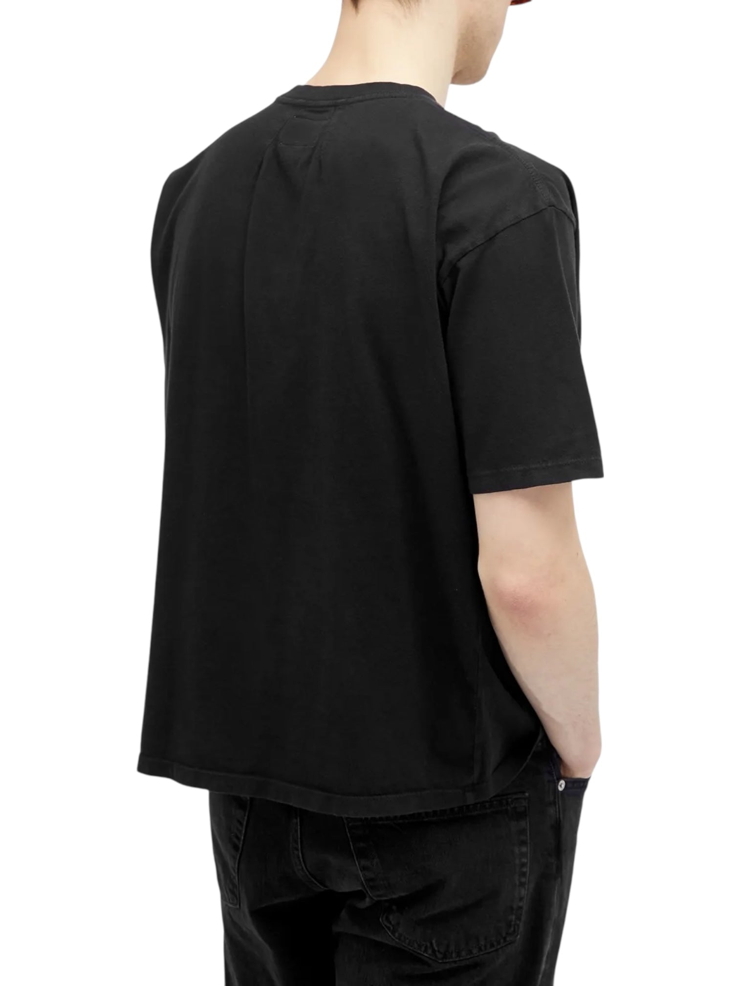 Model wears the RHUDE FLAG TEE BLK by RHUDE, styled with black pants, shown from the back with hands in pockets.