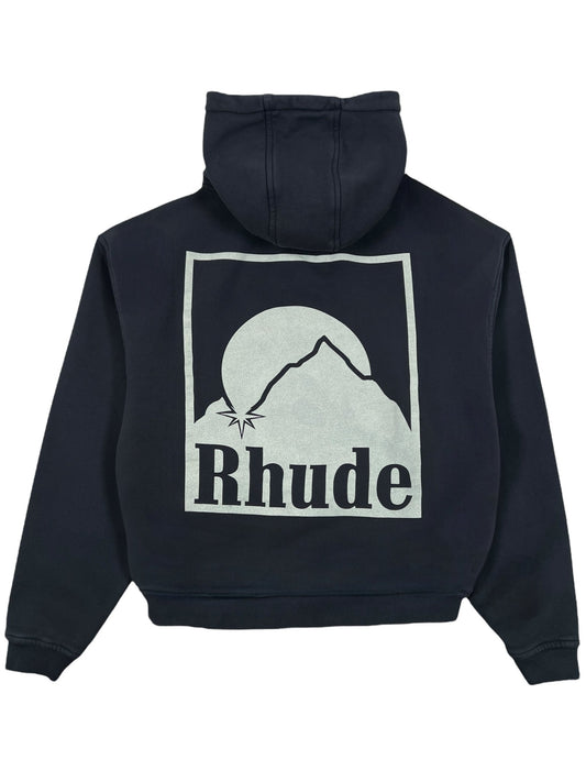 Explore the Rhude Moonlight Badge Hood Black by RHUDE: a black hoodie blending comfort and style with a large back graphic of a mountain, sun, and the word "Rhude" integrated below.