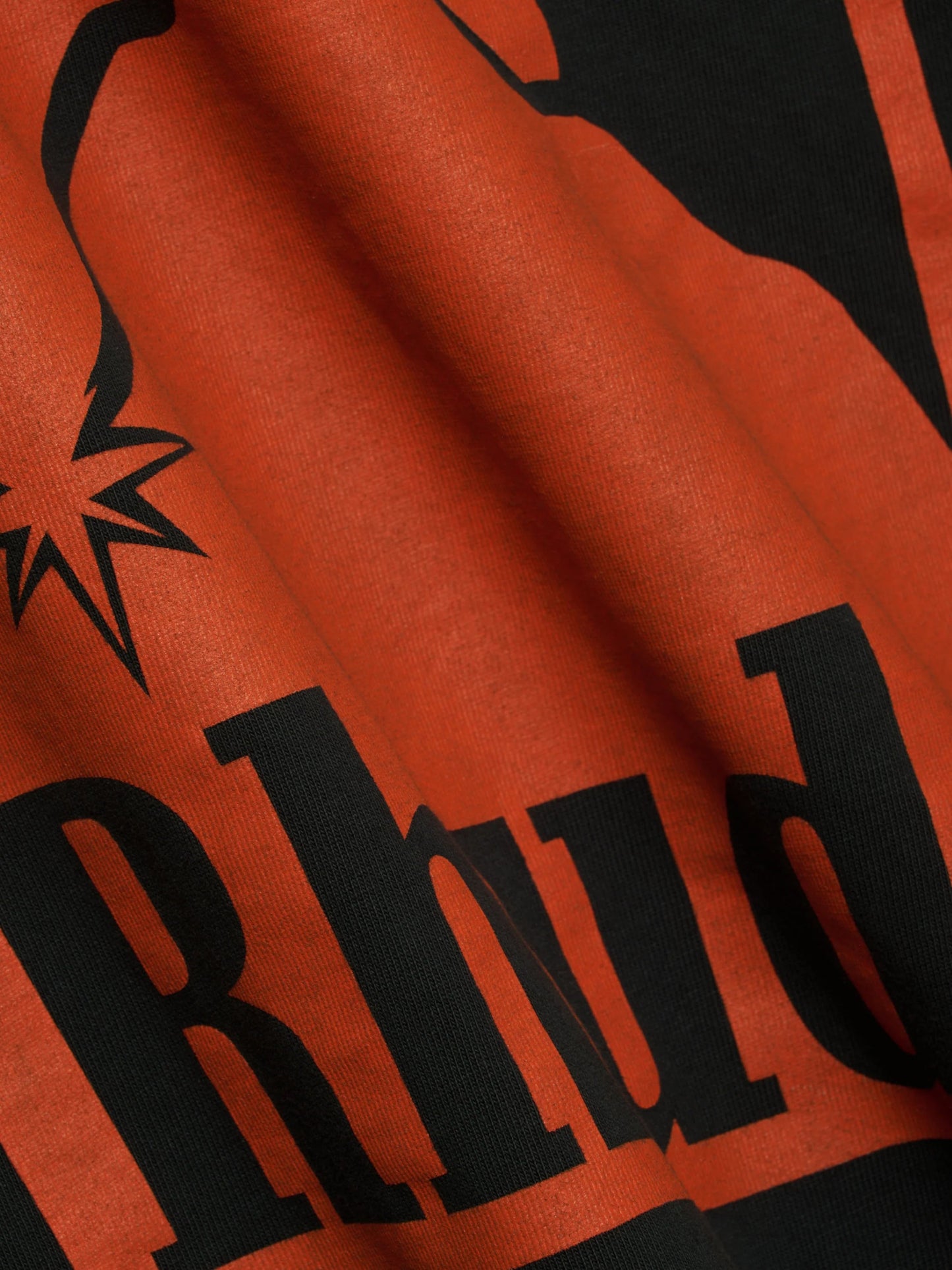 A close-up of black text and a graphic print on premium washed cotton black fabric with visible folds, showcasing the distinctive style of the RHUDE Moonlight Badge LS Tee Vtg Black.