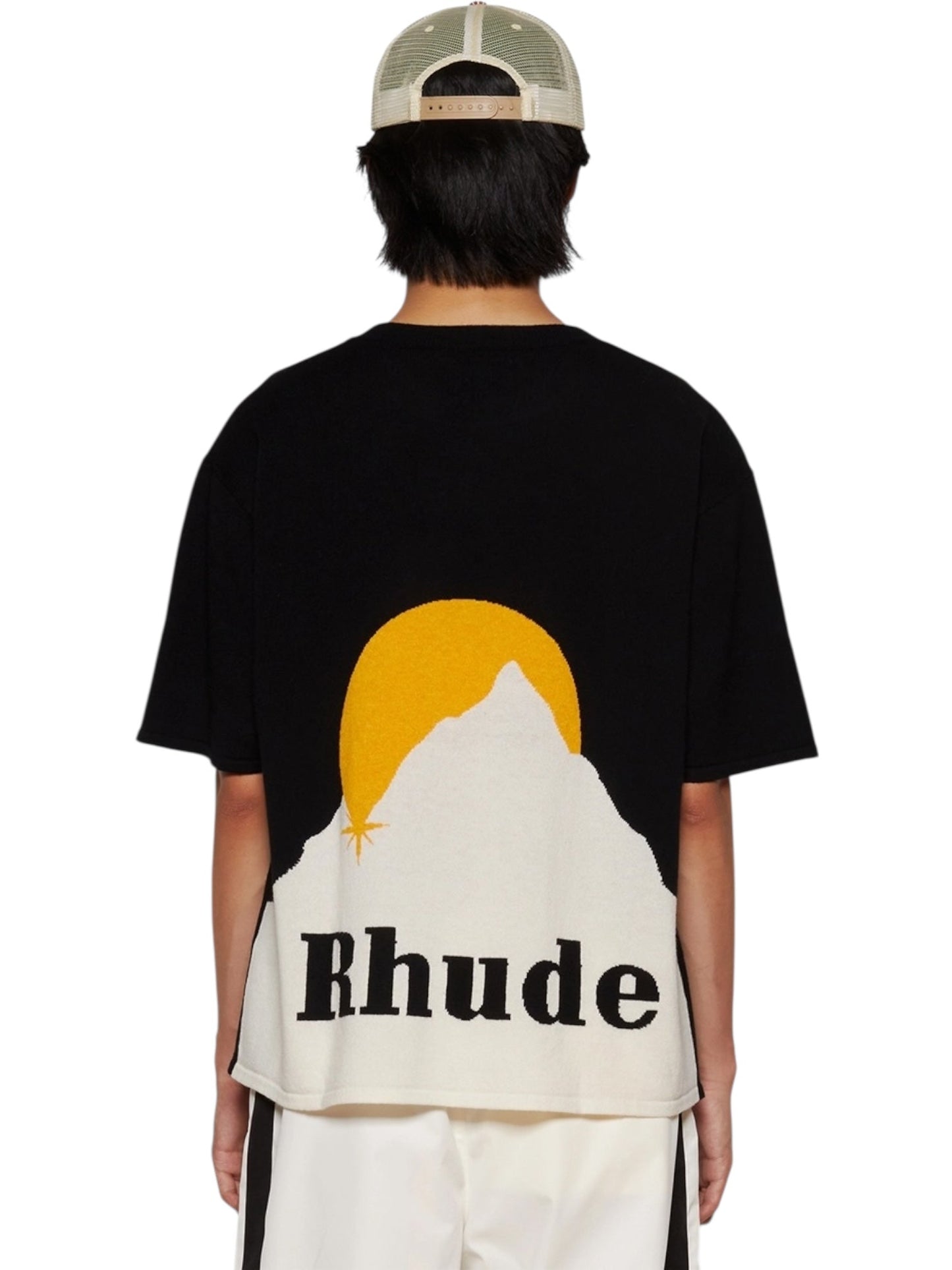 Wearing the RHUDE Moonlight Knit Tee in Black/Cream with a white mountain, yellow sun, and "Rhude" on the back—perfectly styled for Fall/Winter 2024 with a beige mesh cap.