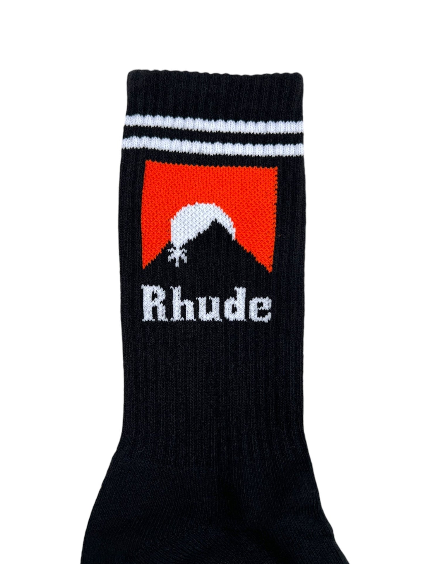 The RHUDE MOONLIGHT SOCK in BLACK/WHITE/ORANGE is crafted from comfortable cotton fabric and adorned with two white stripes at the top. It boasts a striking red and black design with a white silhouette of a mountain and the word "Rhude" prominently displayed in bold white text.