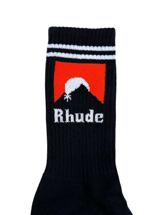 The Rhude Moonlight Sock Black/White/Orange, by RHUDE, is a cotton sock with the "Rhude" logo featuring a white hat silhouette on an orange background, accented by two white stripes at the top.