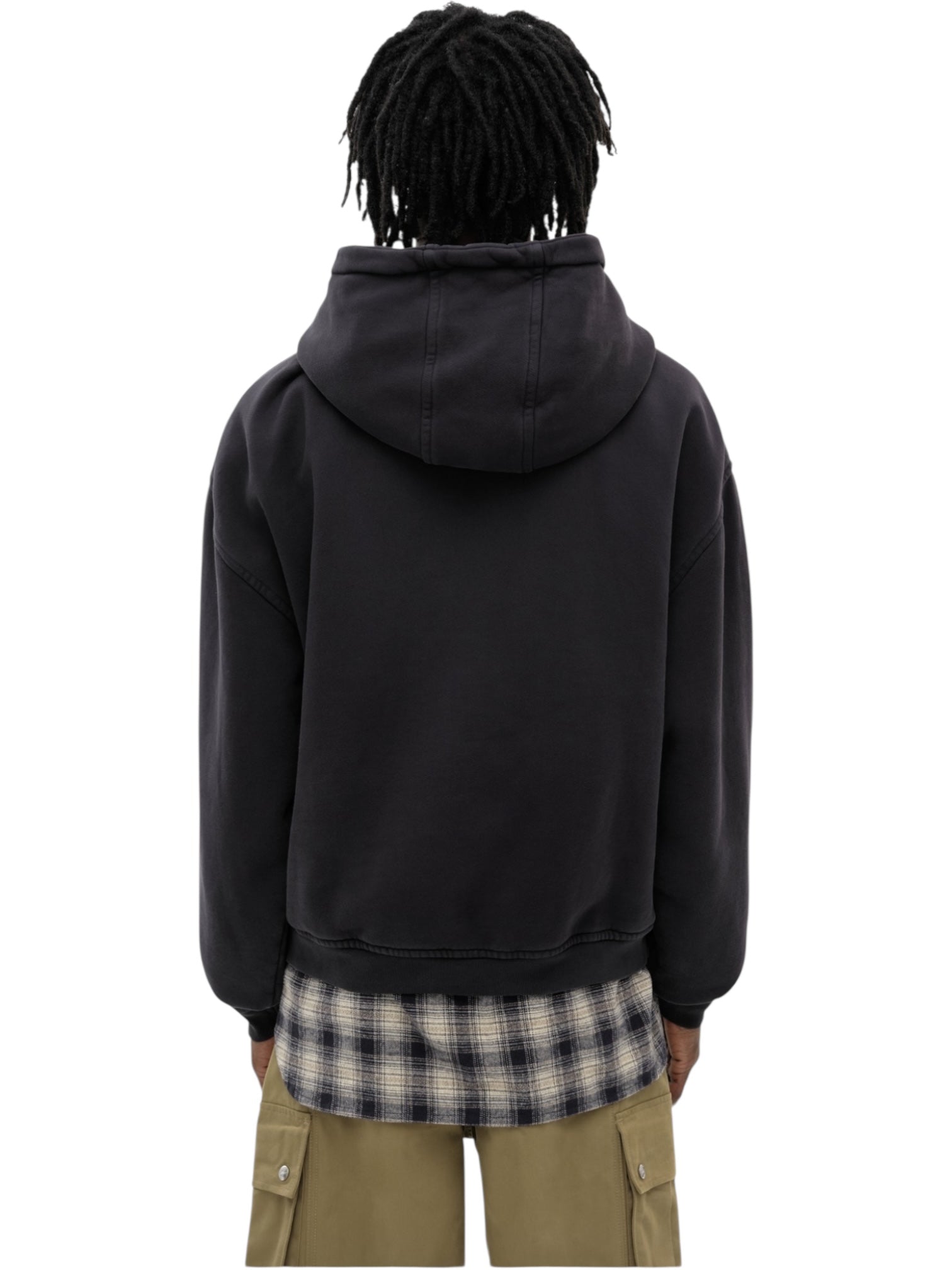 A person with short dreadlocks, facing away from the camera against a white background, wears the RHUDE Premier Hoodie Vtg Black over a plaid shirt and khaki pants.