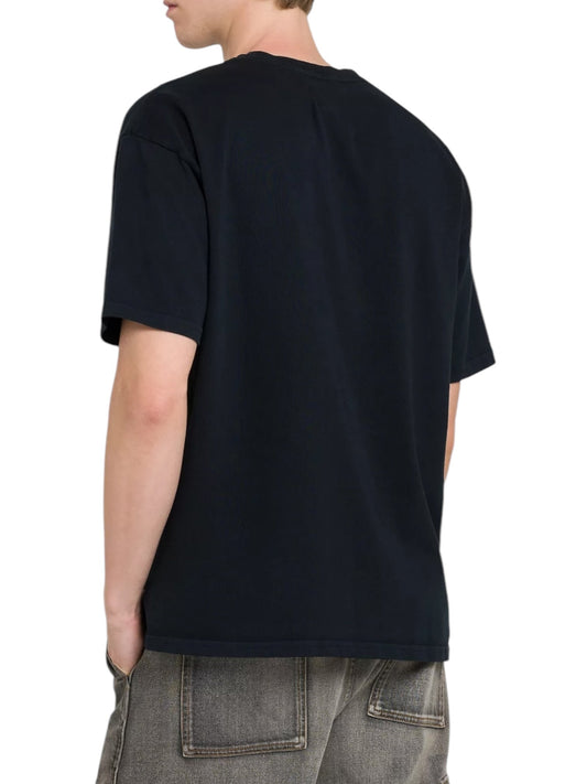 A person wearing a Rhude Saint-Rhude Tee Black by RHUDE and faded jeans is standing with their back to the camera.