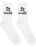 The Rhude Trophy Racing Sock in white/black features a calf-high design with jacquard "RH" logos and "RHUDE" text on the sides, made from a comfortable knit stretch cotton-blend.