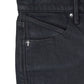 Close-up of the front pocket and waistband of RTA Clayton Coated Black skinny jeans by RTA, featuring a small metallic cross detail near the pocket.