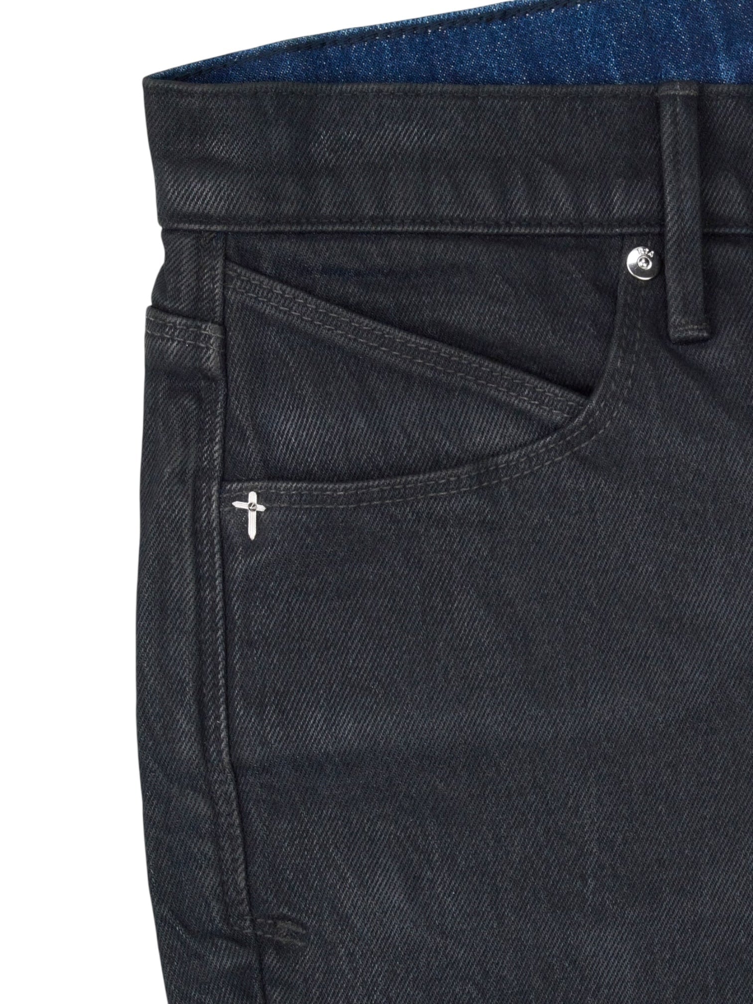 Close-up of the front pocket and waistband of RTA Clayton Coated Black skinny jeans by RTA, featuring a small metallic cross detail near the pocket.