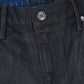 Close-up of the waistband and top front of RTA Clayton Coated Black jeans, featuring a metal button and a black patch label on the inner waistband.