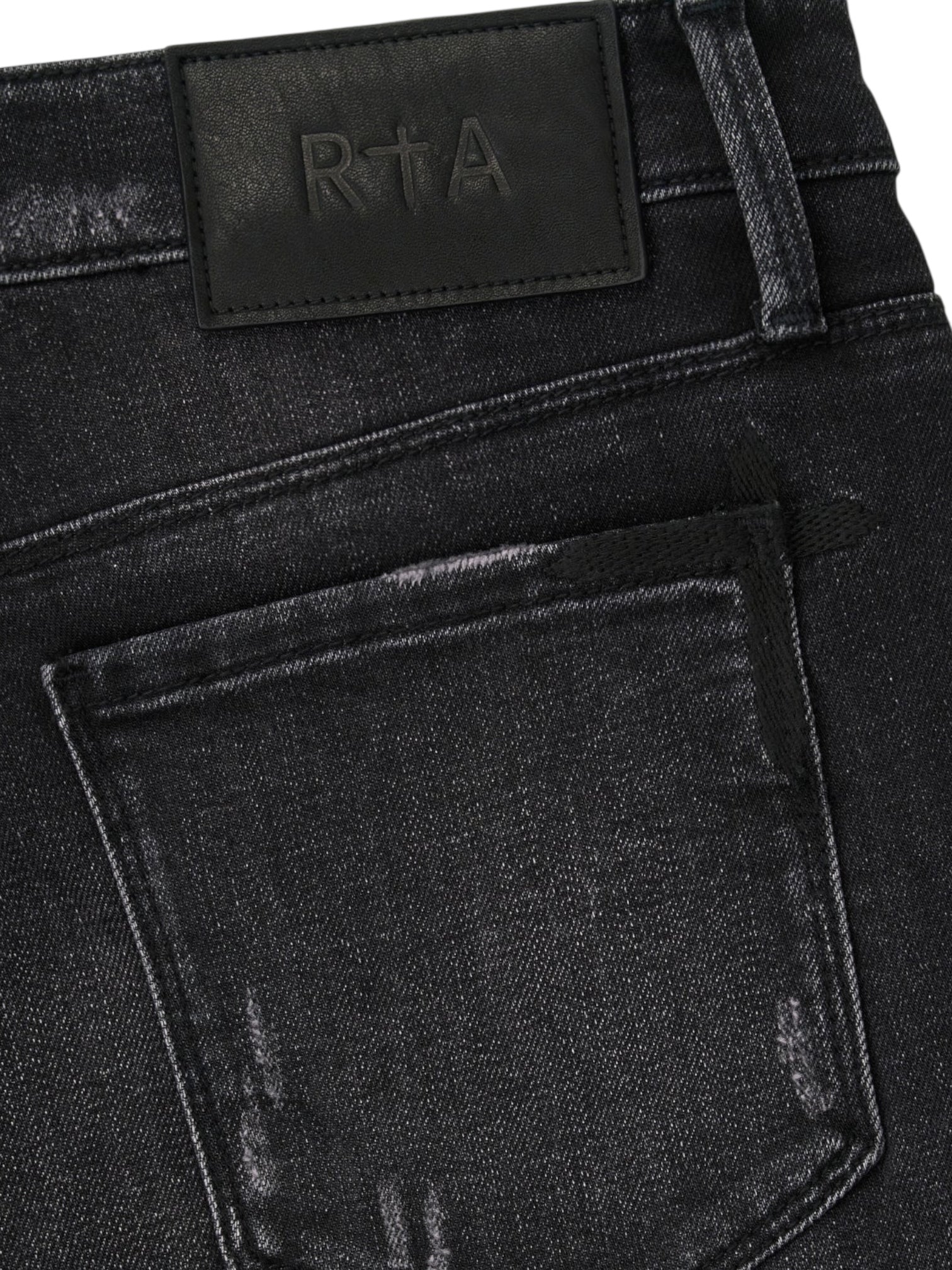 Close-up of the back pocket and waistband of RTA Clayton | Graphite Fade Black skinny jeans, crafted from high-quality denim with a black leather patch embossed with "RTA".