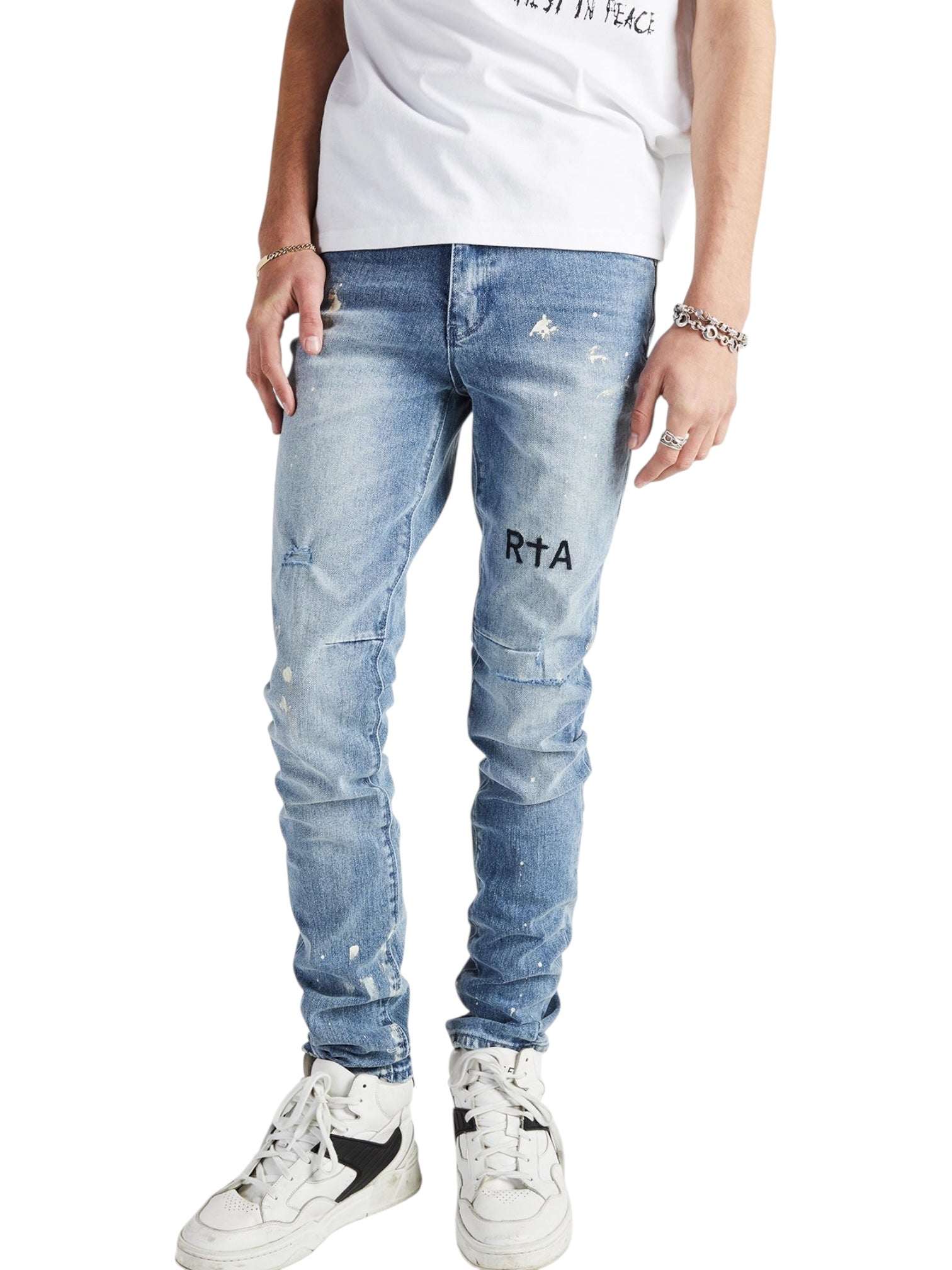 Person wearing RTA Clayton Jean Distressed White Paint Blue by RTA, featuring "RTA" print on the left thigh, paired with white sneakers, a white t-shirt, and bracelets.