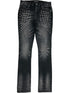 A pair of RTA Olivier Stacked Graphite Fade Cross Black jeans in soft cotton, featuring a stylish graphite fade and silver stud embellishments arranged in rows on the upper front thighs.