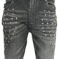 Close-up of RTA Olivier Stacked Graphite Fade Cross Black jeans by RTA, crafted from cotton denim with a graphite fade wash and silver cross-shaped studs in rows on the front upper thighs.