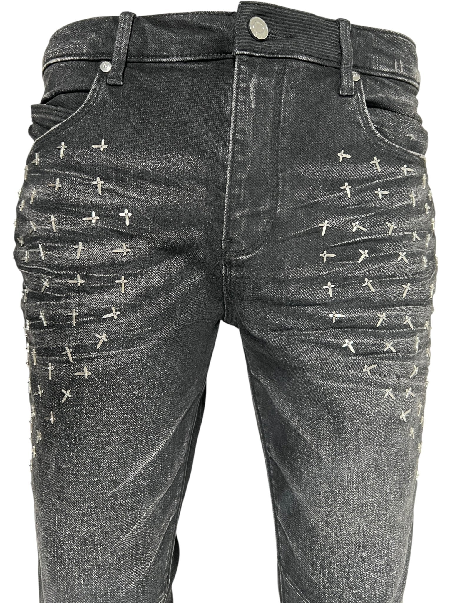 Close-up of RTA Olivier Stacked Graphite Fade Cross Black jeans by RTA, crafted from cotton denim with a graphite fade wash and silver cross-shaped studs in rows on the front upper thighs.