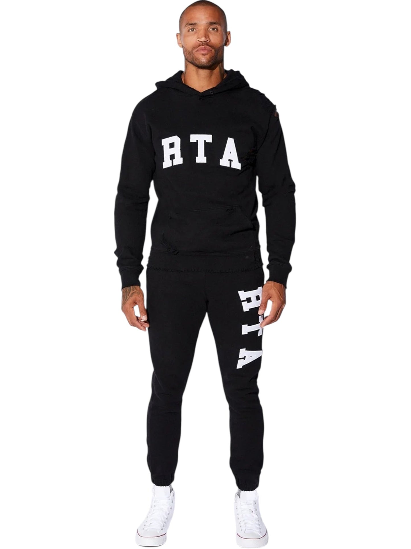 A man stands facing forward in the RTA Owen black collegiate hoodie and sweatpants with white RTA logos, paired with white high-top sneakers, against a white background.