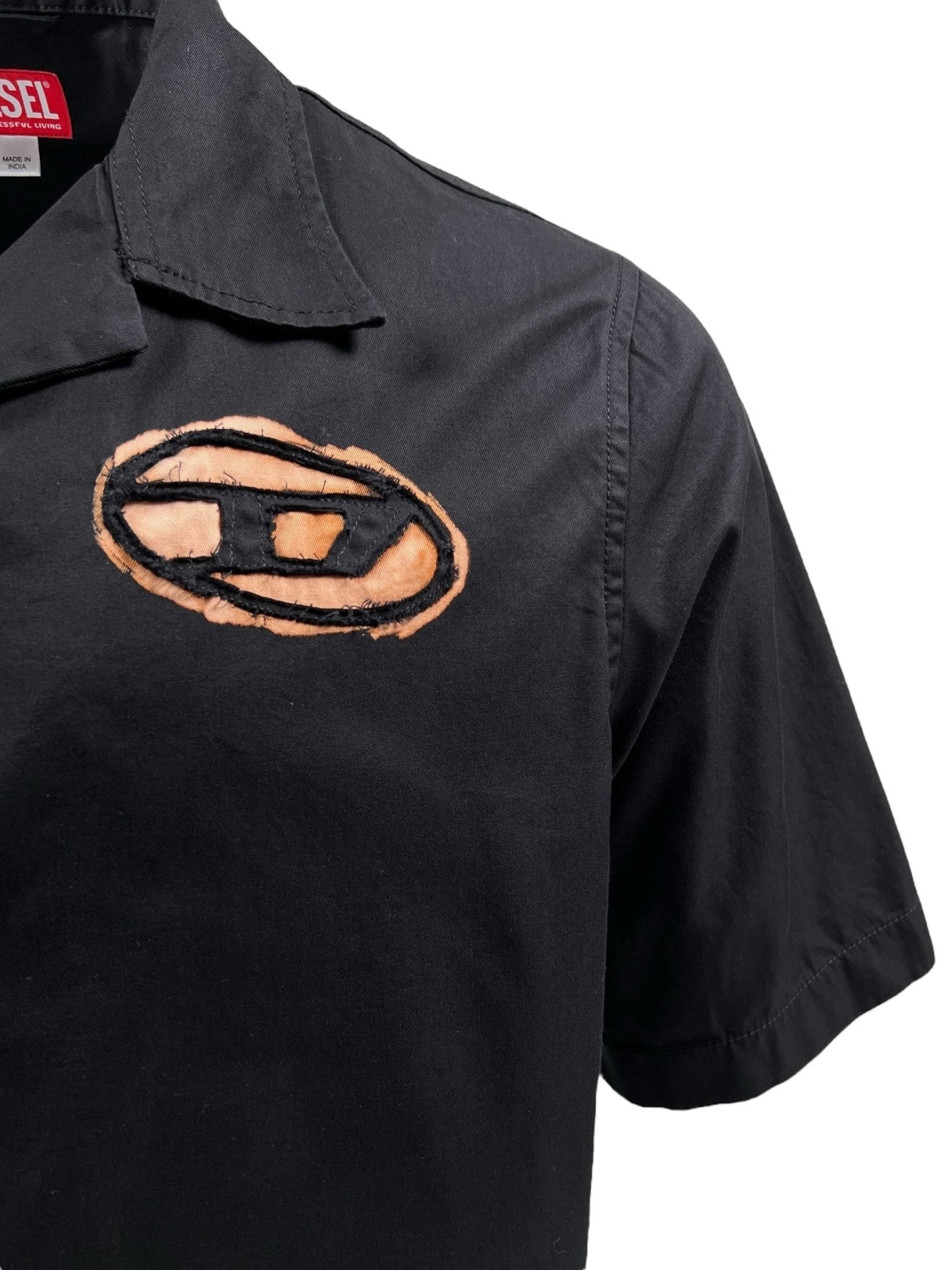 The Diesel S-Stan Bleach Black by DIESEL is a black short-sleeve bowling shirt made from organic cotton, featuring an embroidered oval logo with a stylized "D" near the chest.