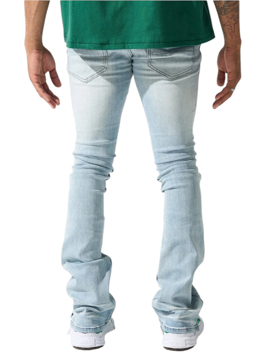 The individual is seen from behind, wearing a green shirt and the stylish Serenede Azul Stacked Jeans Sky by SERENEDE, complemented by crisp white sneakers.