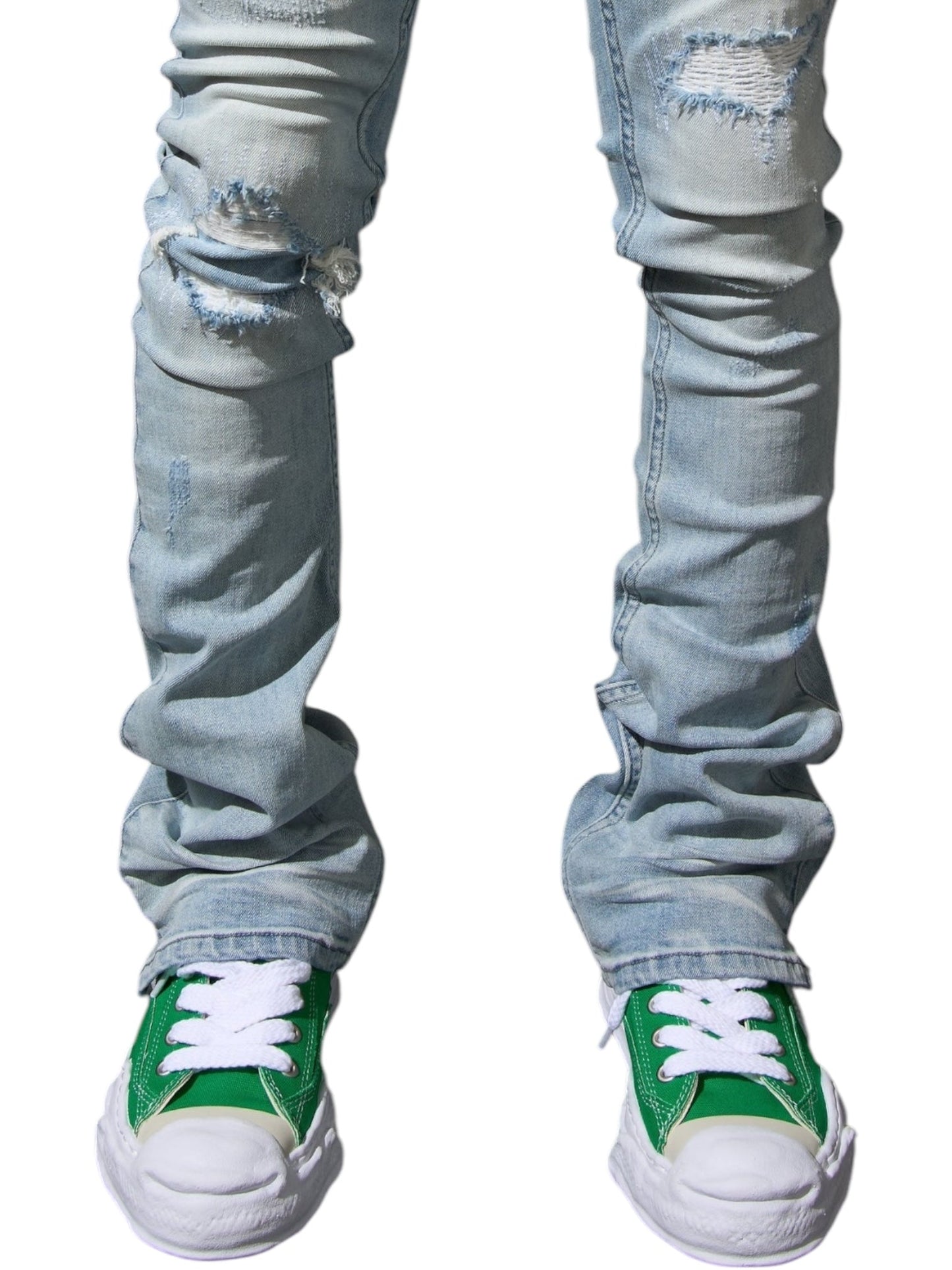 Someone wearing Serenede Azul Stacked Jeans Sky from SERENEDE, with rips in a light blue wash, teamed with green sneakers accented by crisp white laces.