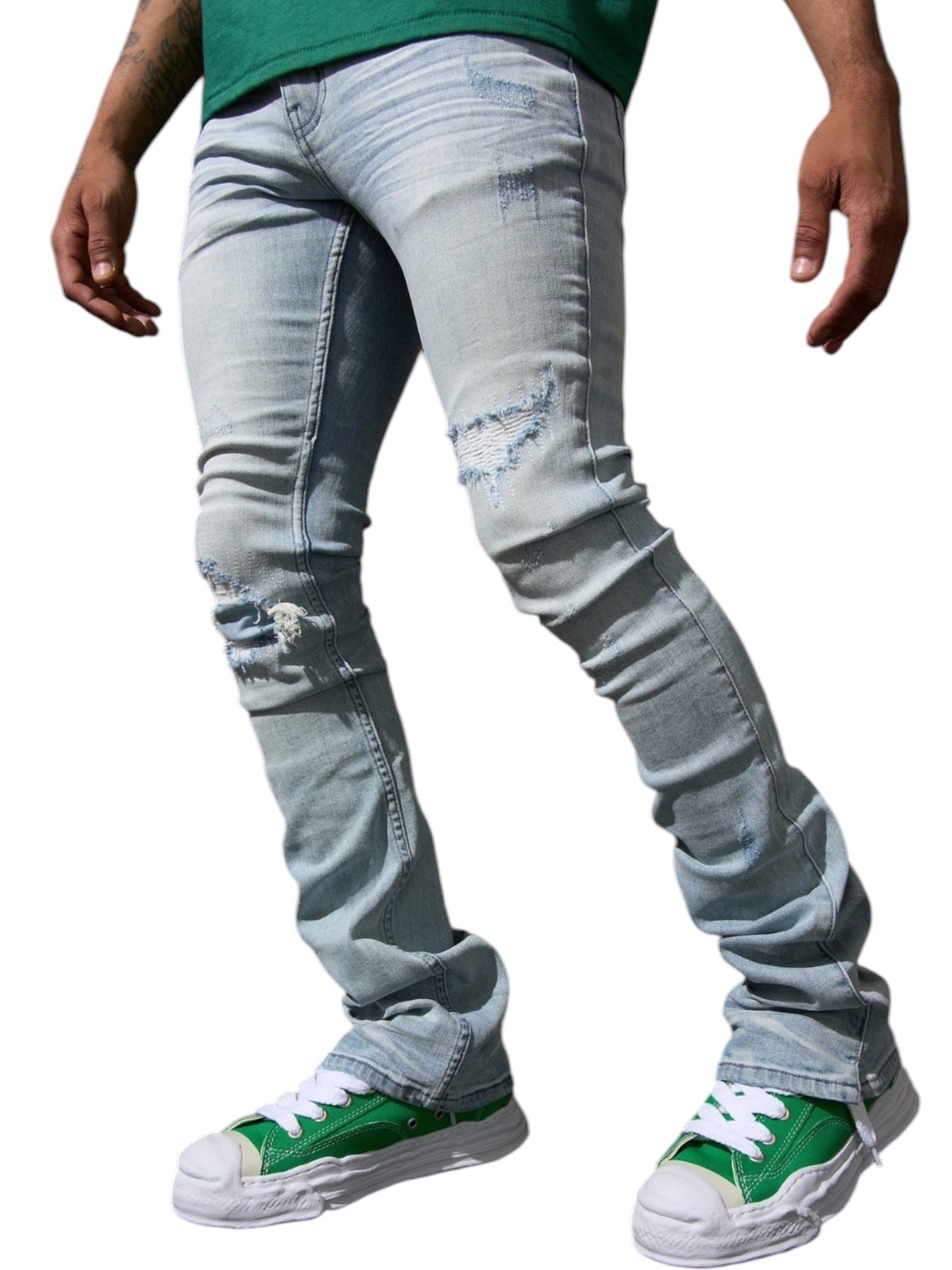 A person wearing SERENEDE's Serenede Azul Stacked Jeans in Sky stands against a white background, paired with green high-top sneakers.