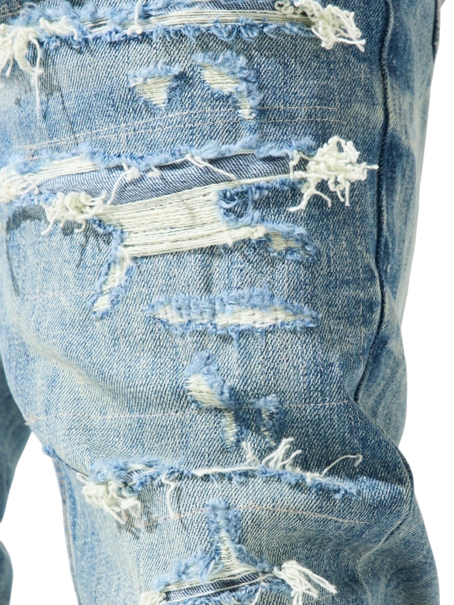 Close-up of Serenede Imperial Straight Leg Jeans in blue by SERENEDE, showcasing heavily distressed details with multiple frayed tears and patches.