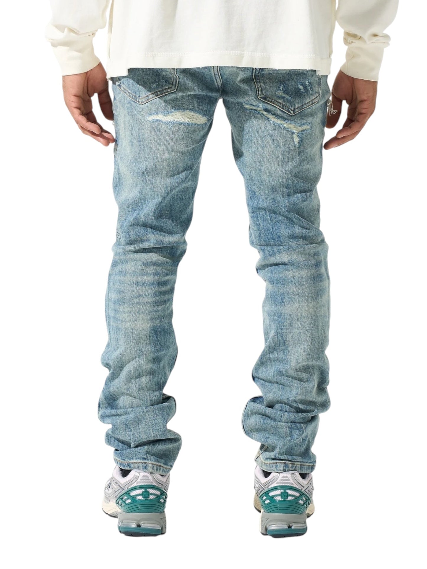 Back view of a person wearing SERENEDE's Serenede Imperial Straight Leg Jeans in blue, paired with a white shirt and sneakers featuring teal accents.