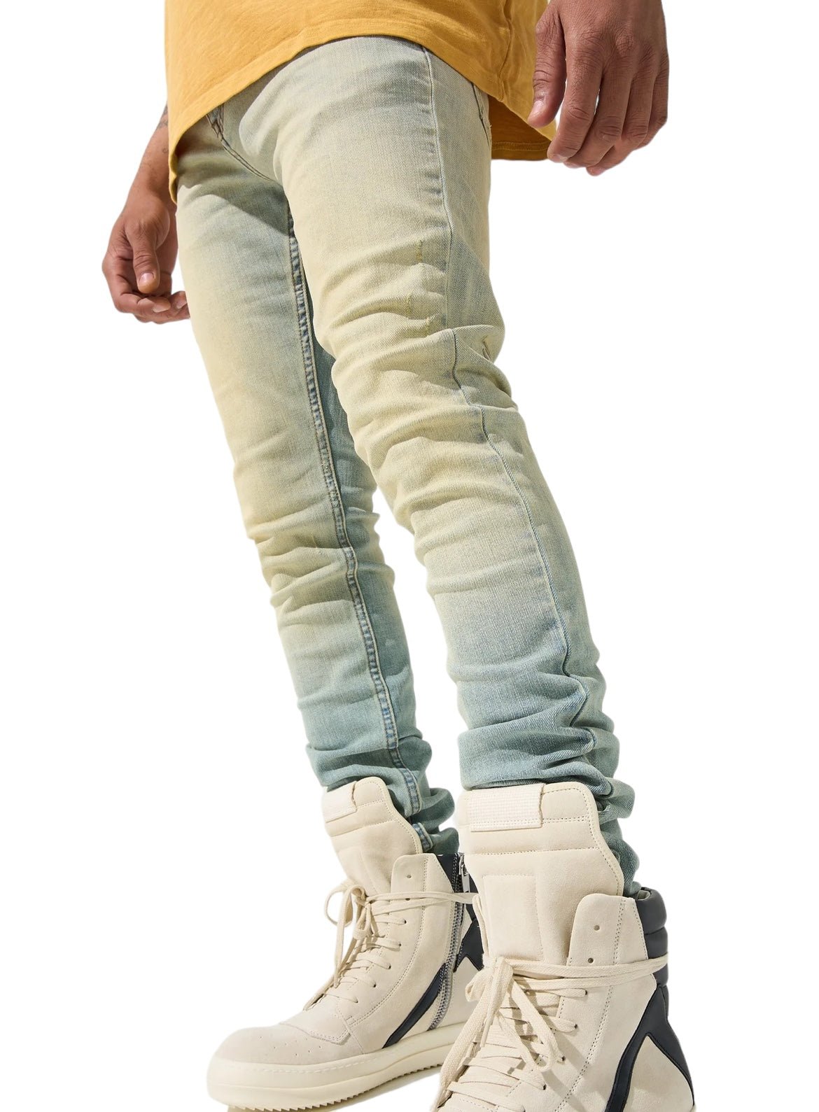 A person wearing SERENEDE LIMESTONE JEANS EARTH YELLOW by SERENEDE, a yellow shirt, and beige high-top sneakers stands against a white background.