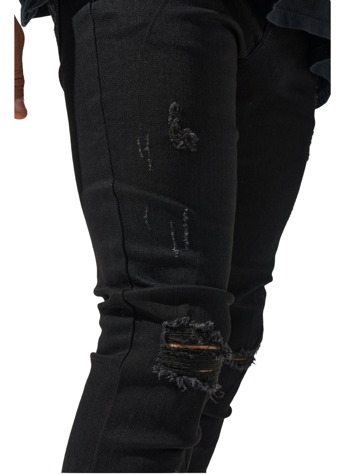 Close-up of a SERENEDE MIDNIGHT BLACK JEANS with visible rips and frayed edges on the right leg.