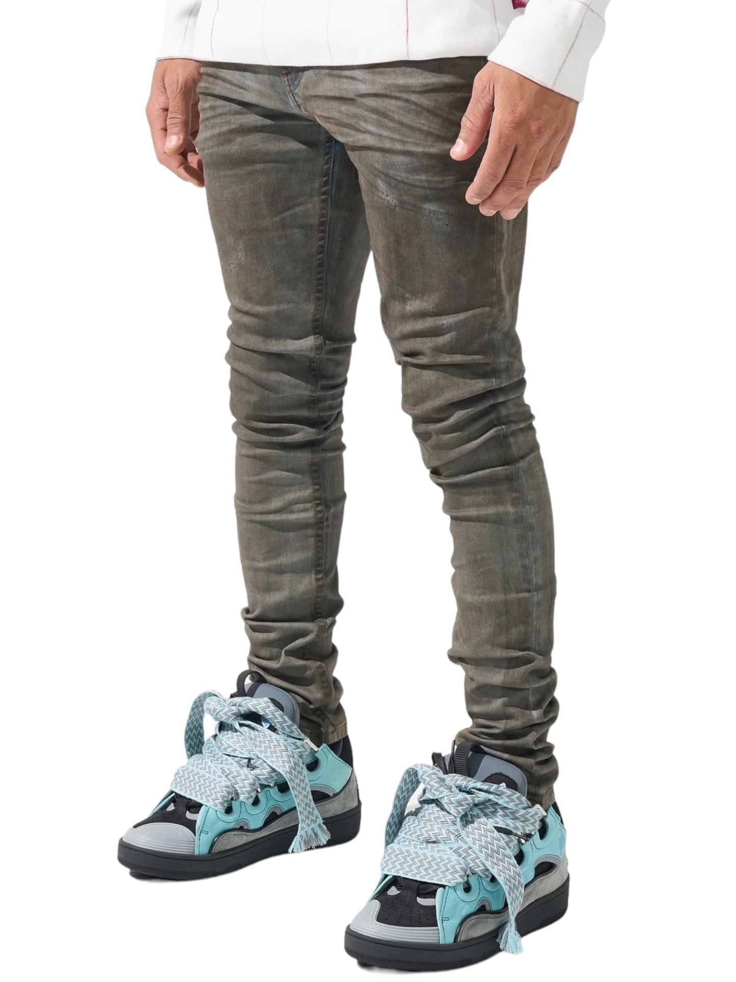 Person wearing SERENEDE NIGHTFALL JEANS NIGHTBLUE by SERENEDE, a distressed skinny-fit style in dark grey and blue wash, paired with teal sneakers featuring oversized laces, standing against a white background.