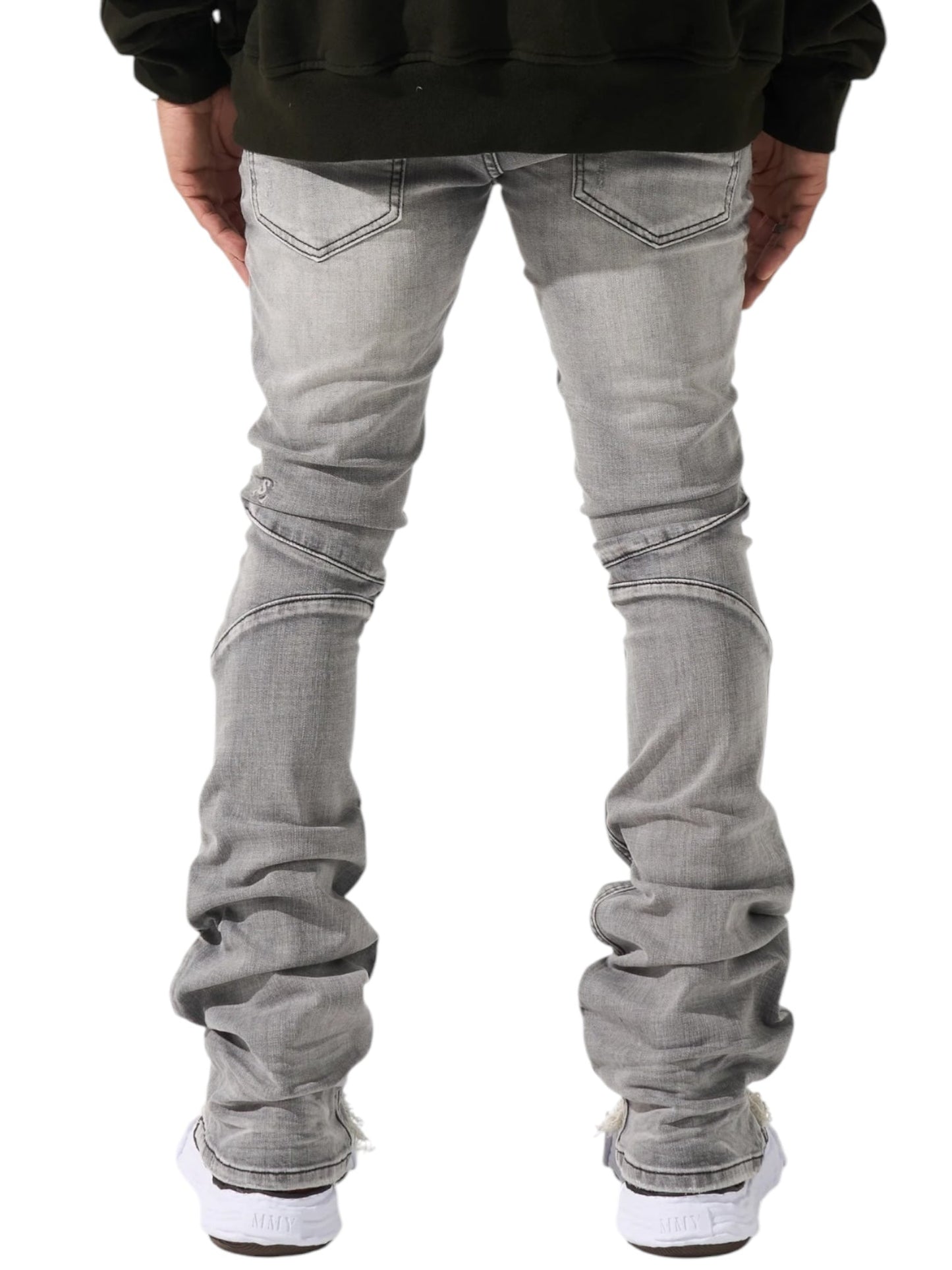 Rear view of a person in SERENEDE Noctis Stacked Jeans Grey and white sneakers, against a crisp white background.