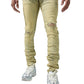A person wearing SERENEDE SOL JEANS RISE, a pair of distressed, light beige men's jeans made of stretch cotton with rips on the knees, a white shirt, and white athletic shoes. The photo shows the lower half of the body.