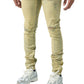 Man wearing SERENEDE SOL JEANS RISE, distressed yellow skinny jeans crafted from stretch cotton by SERENEDE, paired with white sneakers.