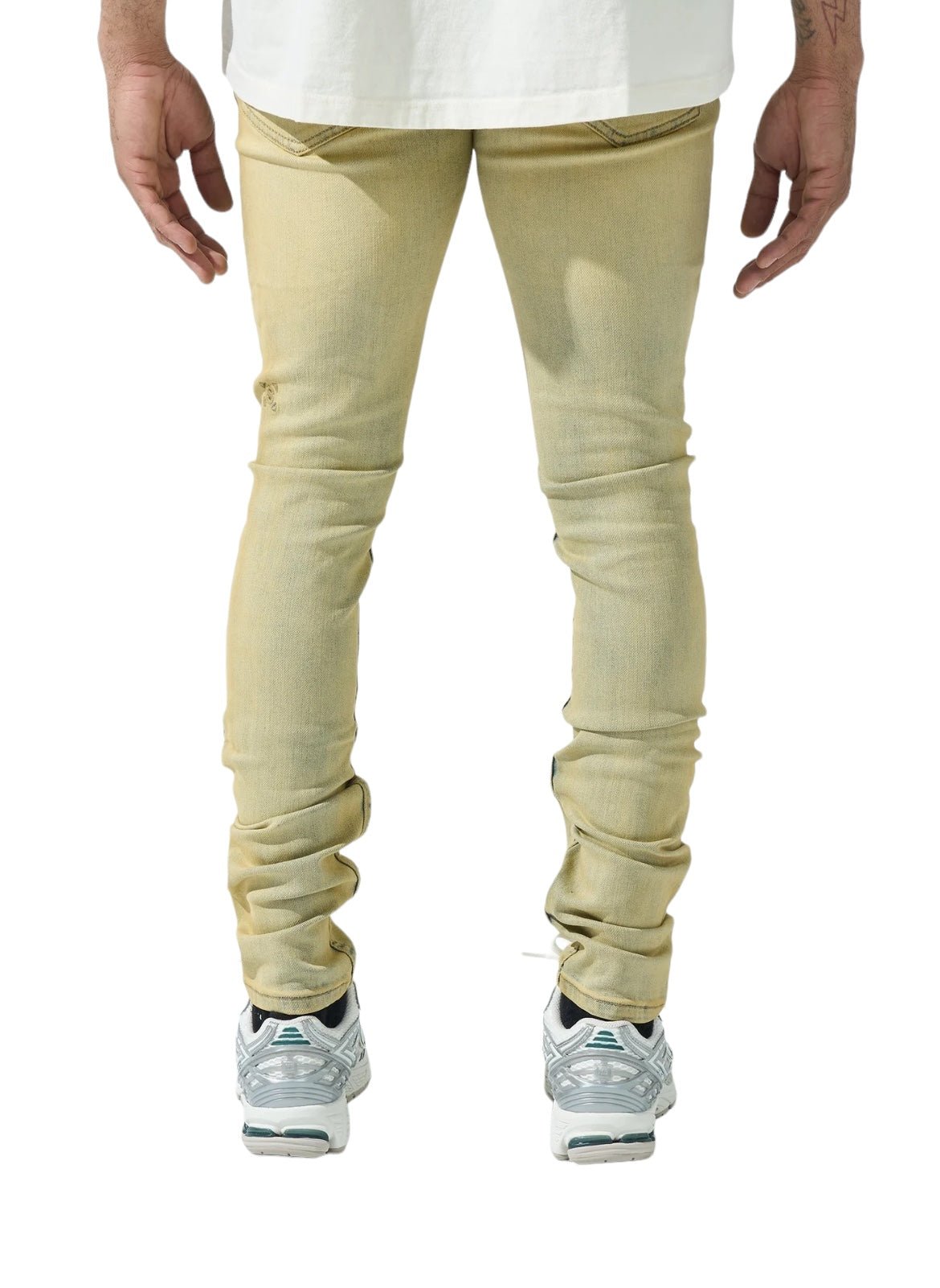 A person is standing, wearing slim fit, light-colored SERENEDE SOL JEANS RISE made from stretch cotton, a crisp white shirt, and silver sneakers, viewed from behind.