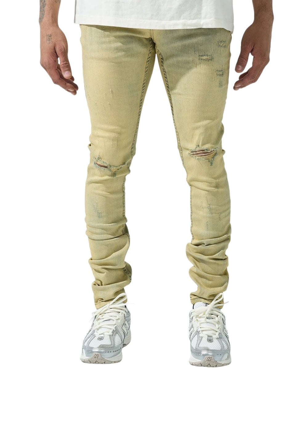 A person wearing SERENEDE SOL JEANS RISE, which are distressed beige slim fit jeans made of stretch cotton, along with a white shirt and white sneakers, stands facing forward on a white background.