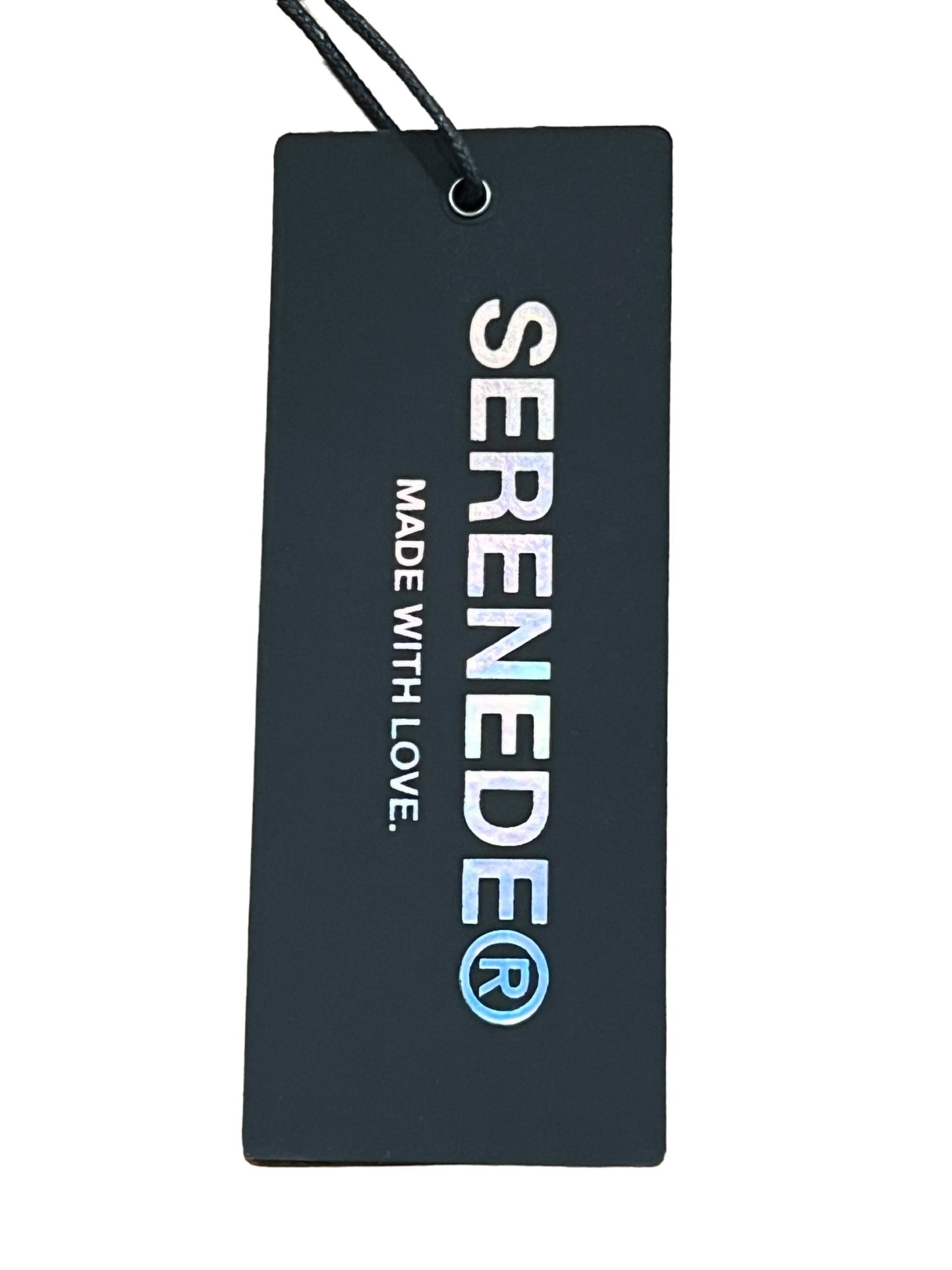 A black clothing tag with the word "SERENEDE TIMBER WOLF ARTIC GREY" printed in white, followed by "made with love" in smaller letters, isolated on a white background.