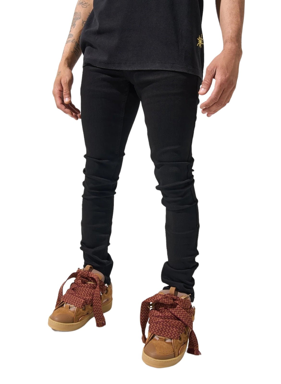 Person wearing SERENEDE VANTA 11 JEANS BLACK, a black shirt made from premium fabric, and brown sneakers with patterned laces, standing against a white background.