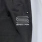 Close-up of black fabric showcasing the SINCLAIR brand's signature white embroidered 'S' logo and "SINCLAIR" text, echoing the refined style of Sinclair SMB65 Tech Logo Track Pant Black.
