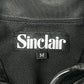 Close-up of a black SINCLAIR SMT190 Tech Logo Track Jacket featuring an embroidered "Sinclair" logo and a size "M" tag.