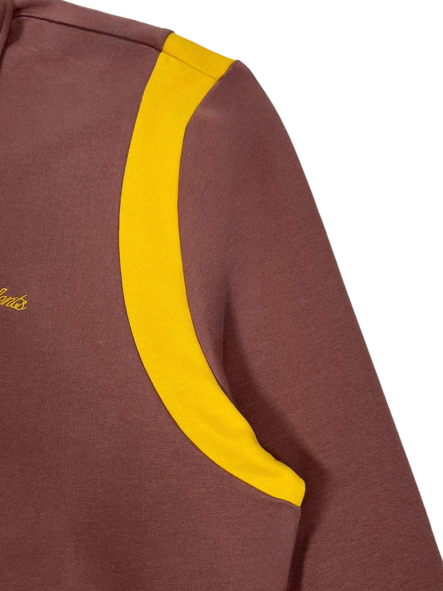 Close-up of the Students Callum long sleeve polo shirt in brown, featuring a yellow stripe on the shoulder and crafted from cozy French terry cotton by STUDENTS.