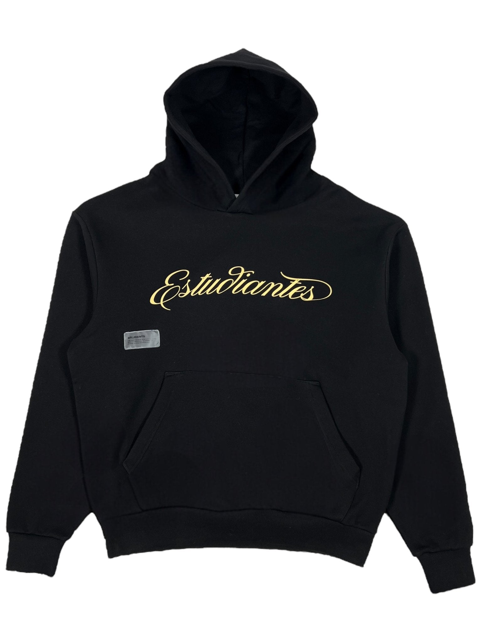 The Students Estudiantes Pullover Hood in black, by STUDENTS, features "Estudiantes" in gold cursive on the front. It's made from 100% cotton and includes a kangaroo pocket with a small rectangular label on the left side.