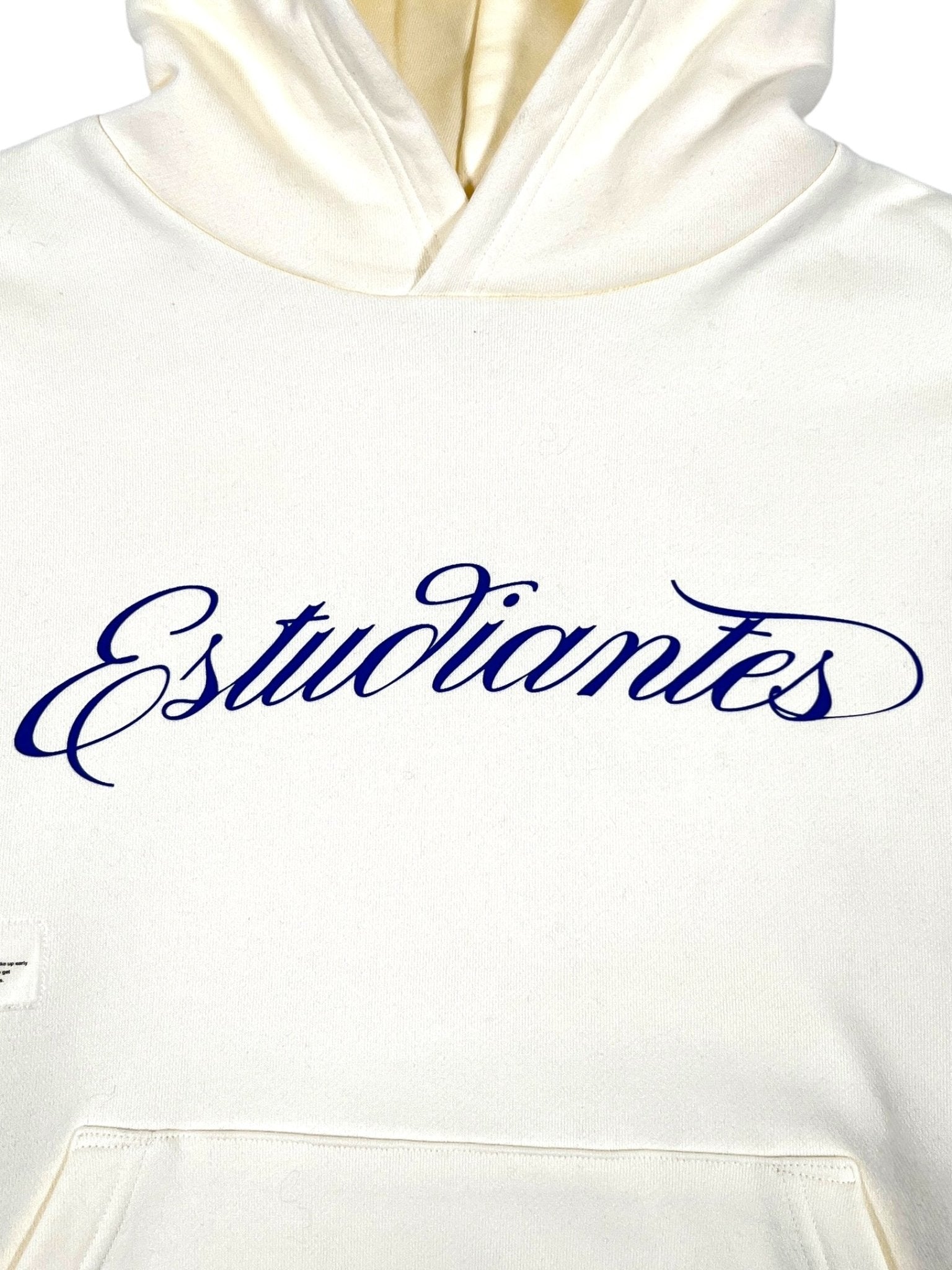 The Students Estudiantes Pullover Hoodie by STUDENTS is a crisp white, 100% cotton hoodie featuring "Estudiantes" in blue cursive across the chest—ideal for students.