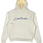 The Students Estudiantes Pullover Hood Nude by STUDENTS is a 100% cotton hoodie featuring "Estudiantes" in cursive blue on the front, complete with a convenient front pocket and cozy drawstring hood for ultimate comfort.