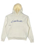 The Students Estudiantes Pullover Hood Nude by STUDENTS is a 100% cotton hoodie featuring "Estudiantes" in cursive blue on the front, complete with a convenient front pocket and cozy drawstring hood for ultimate comfort.