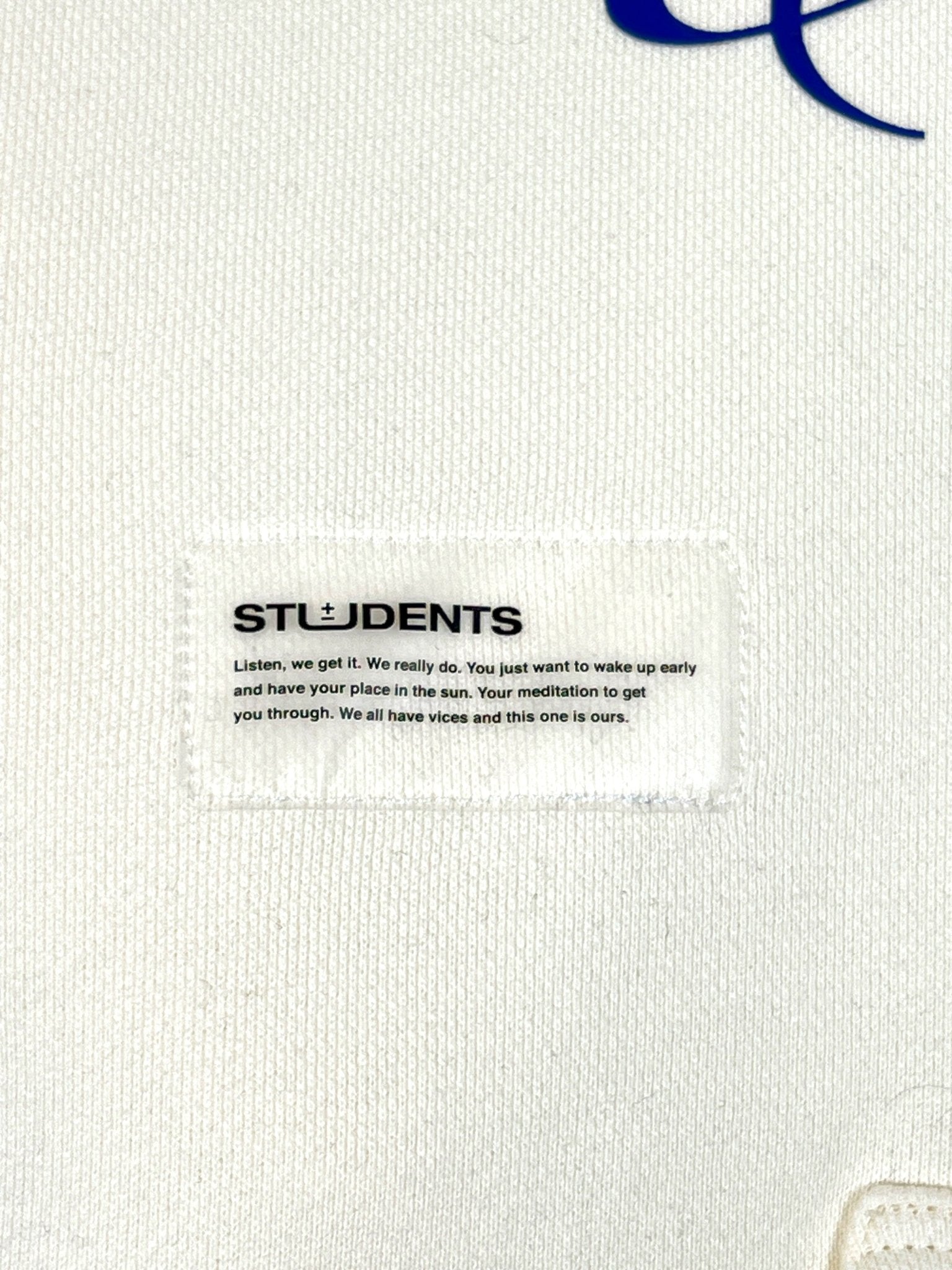 The "Students Estudiantes Pullover Hood Nude" by STUDENTS features a white fabric label with "STUDENTS" text, motivating you to wake up early and embrace imperfections. It's crafted from 100% cotton for ultimate comfort and inspiration.