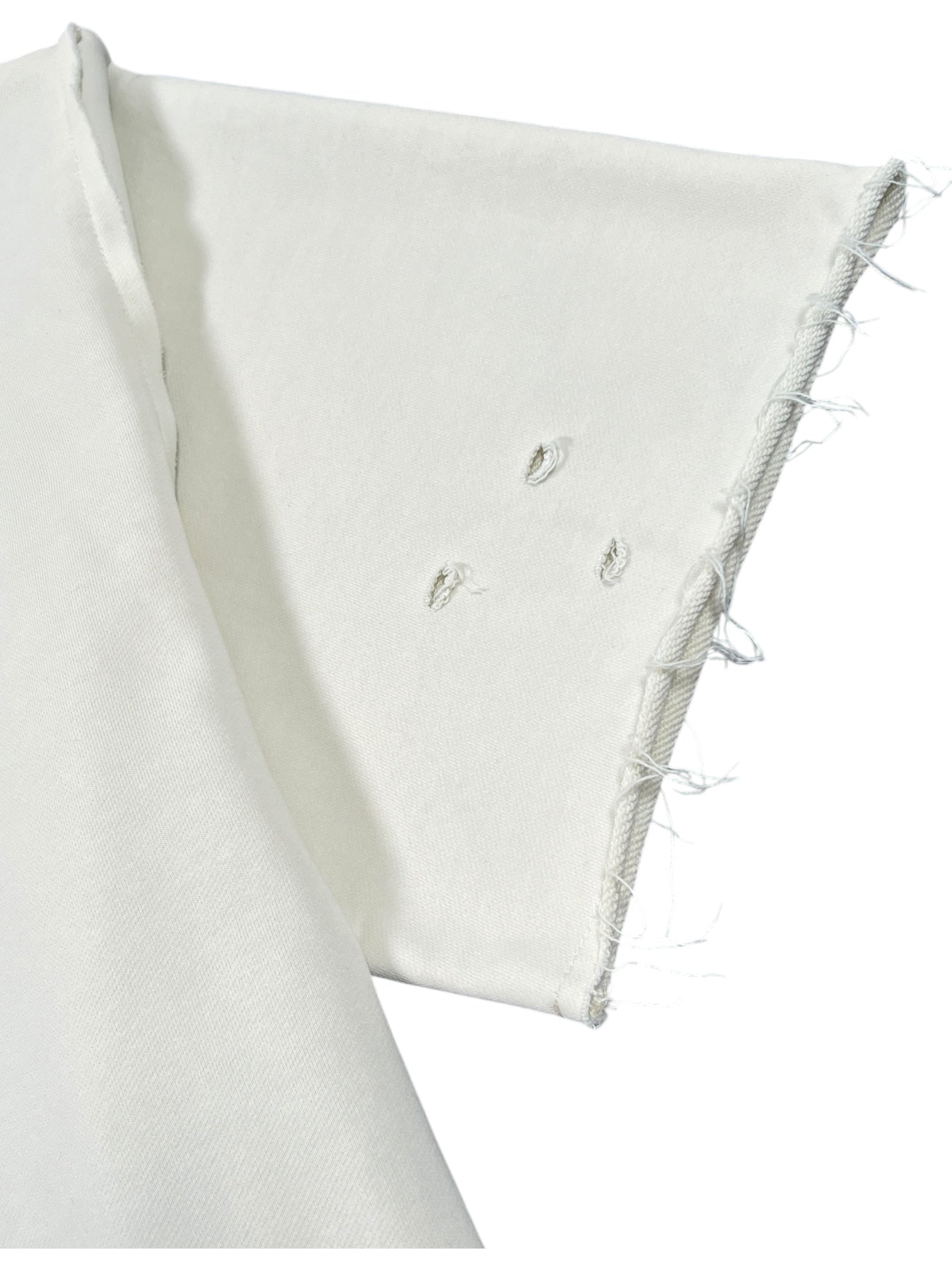Close-up of the UNTITLED ARTWORKS Untitled Artworks Crewneck Short Sleeve Cream, a 100% cotton oversized t-shirt with a white short sleeve, unfinished frayed hem, and three small holes near the seam.