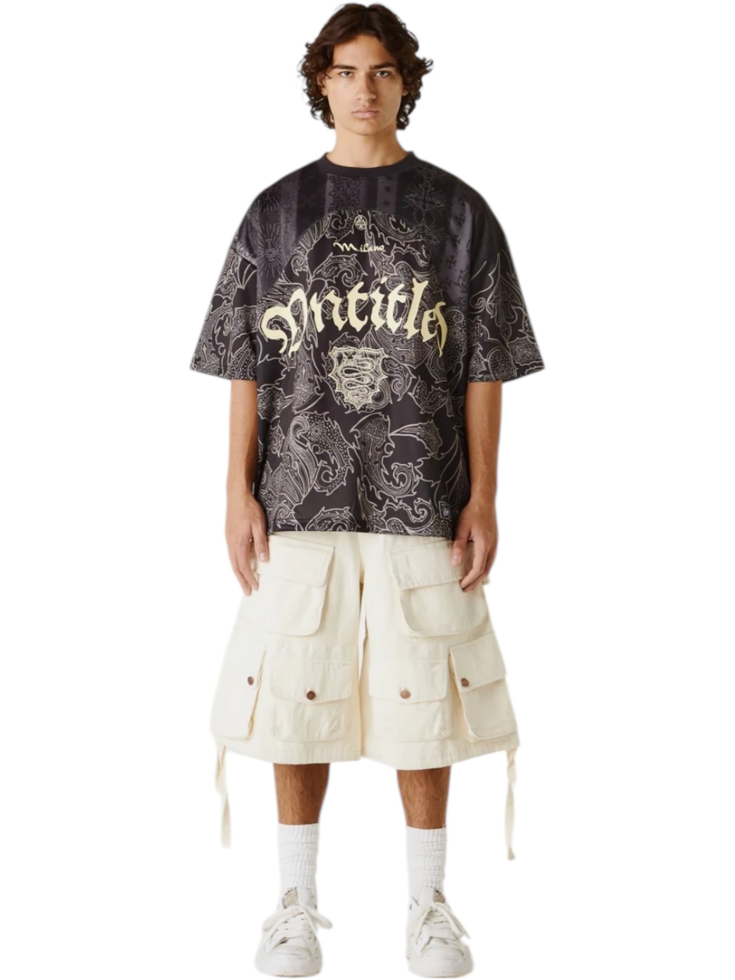 A person stands facing forward, wearing the UNTITLED ARTWORKS Untitled Artworks Sport Jersey Tee Black, cream cargo shorts with large pockets, white socks, and white sneakers.