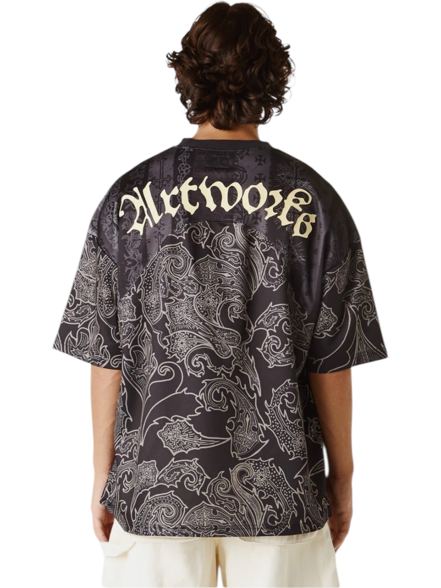 A person wears the UNTITLED ARTWORKS Untitled Artworks Sport Jersey Tee Black, a black polyester short-sleeve shirt with white abstract patterns and bold "Artworks" lettering on the back, capturing a modern streetwear vibe.