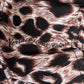 A close-up of the leopard print fabric captures the wild allure of the VERSACE E72GAZK08-EZG089-EY4V bucket hat, with "Versace Jeans Couture" elegantly printed in black over the design.